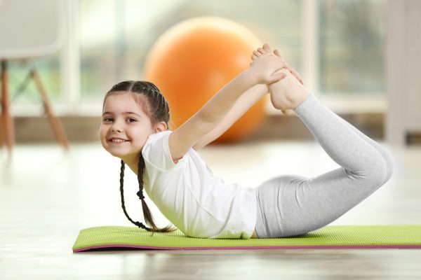 Little cute girl practicing yoga pose on a mat indoor